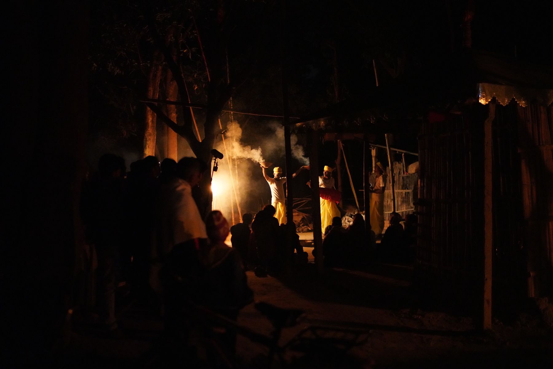 Night-time village ritual with flames and smoke