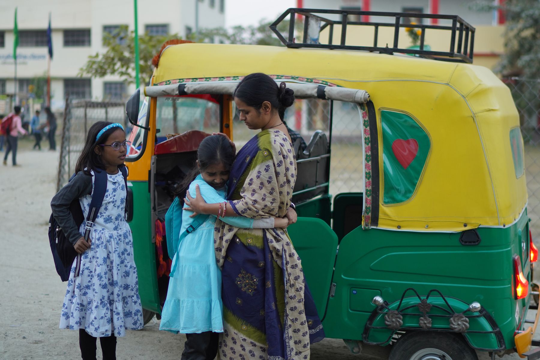Mother embraces daughter outside school auto-rickshaw